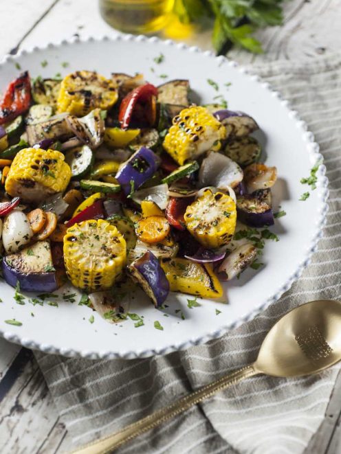 Verdure grigliate con mais, melanzane, zucchine, peperoni e cipolla, cosparse di prezzemolo tritato