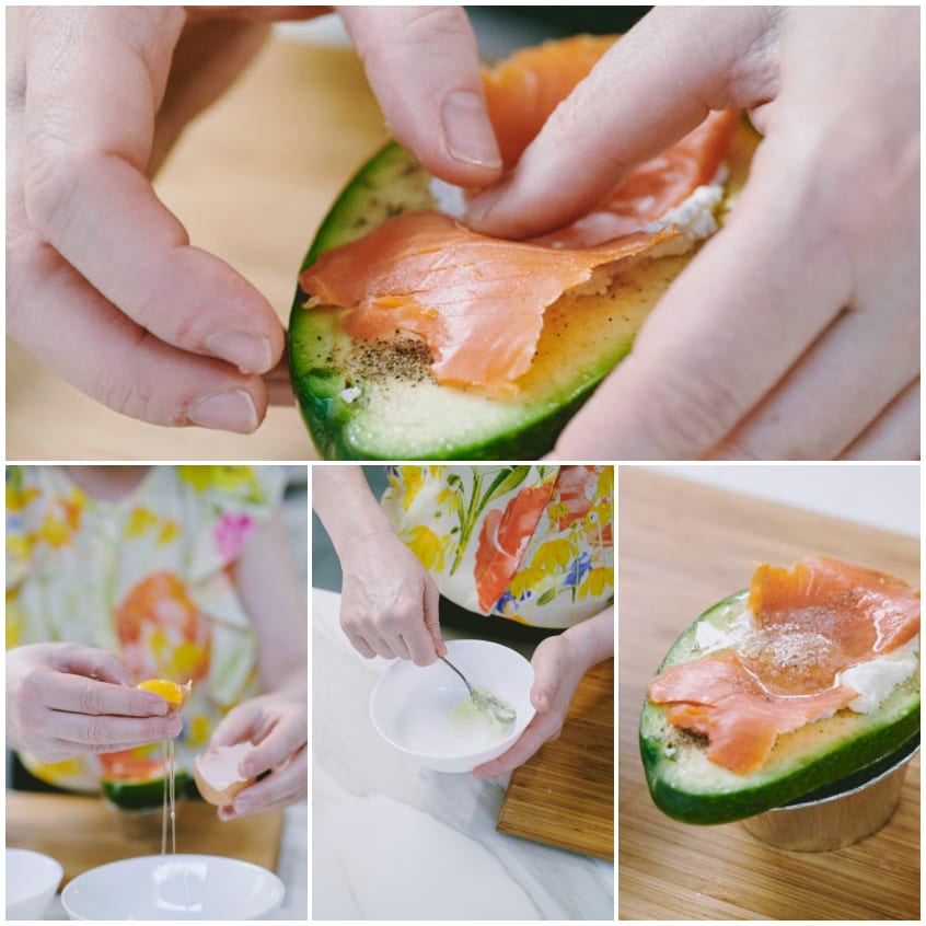 Mani che adagiano salmone affumicato su una metà di avocado farcita con caprino