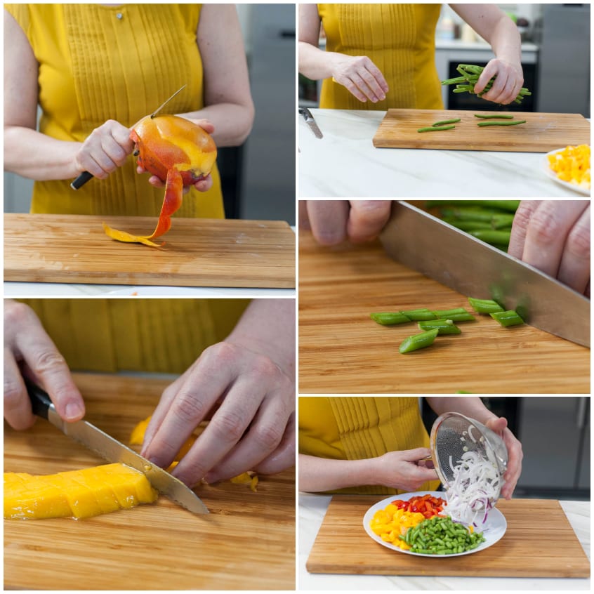 Preparazione dell'insalata: mango sbucciato e tagliato a pezzi, fagiolini affettati di sbieco e cipolla riuniti sul tagliere