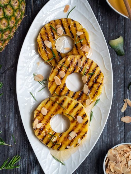 Ananas grigliato a fette con crema al centro, mandorle a lamelle e aghi di rosmarino