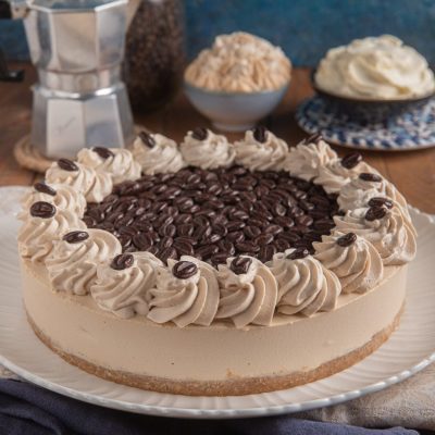 Cheesecake al caffè decorata con ciuffi di panna al caffè e chicchi di caffè al cioccolato