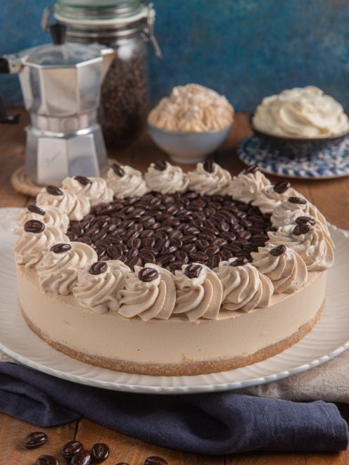 Cheesecake al caffè decorata con ciuffi di panna al caffè e chicchi di caffè al cioccolato
