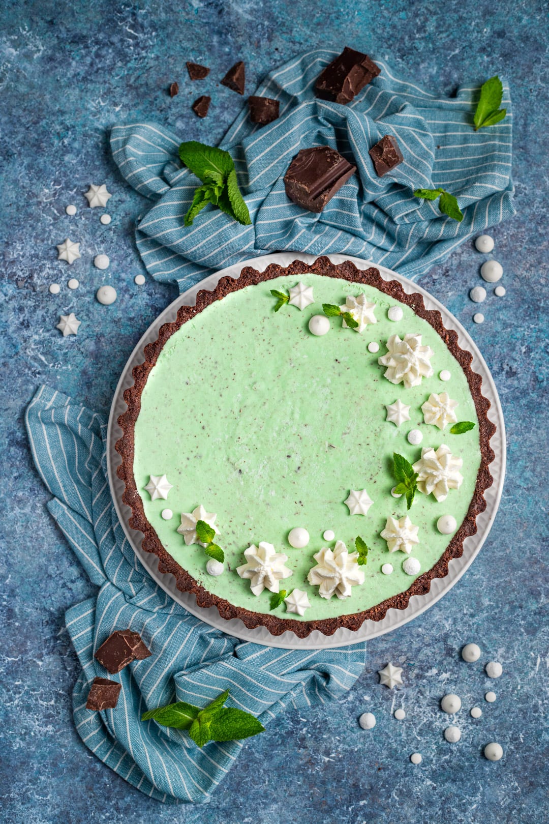 Cheesecake cioccomenta decorata con ciuffetti di panna montata, meringhette e foglie di menta fresca