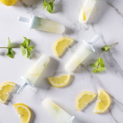 Ghiaccioli alla menta e limone con fette di limone fresco e foglie di menta sparse