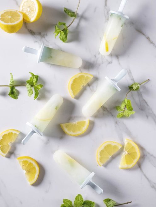 Ghiaccioli alla menta e limone con fette di limone fresco e foglie di menta sparse