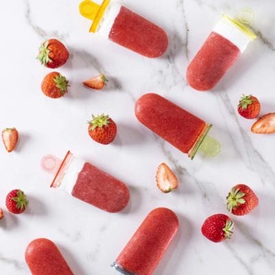 Ghiaccioli panna e fragole disposti con fragole fresche intere e a fette