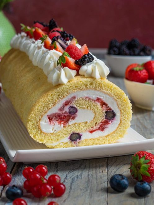 Rotolo con panna e frutti di bosco farcito, con fragole, mirtilli e more in cima