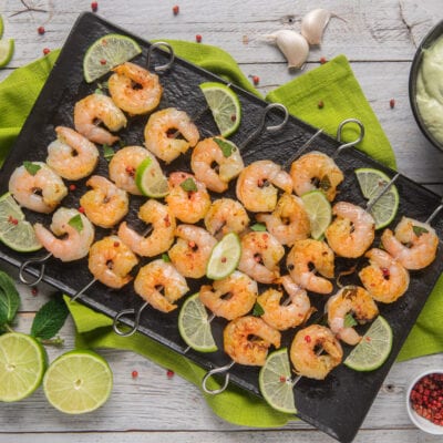 Spiedini di gamberi grigliati con fettine di lime e pepe rosa