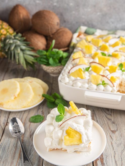 Tiramisù all'ananas e cocco con panna montata, pezzi di ananas e foglioline di menta