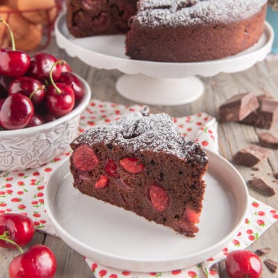 Torta al cioccolato e ciliegie in fetta, con le ciliegie visibili nell'impasto e zucchero a velo