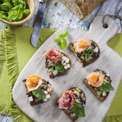 Bruschette con radicchio guarnite con salmone affumicato, salame e foglie di basilico fresco