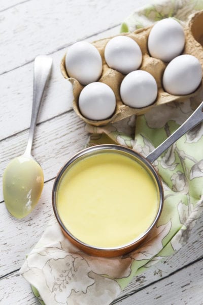 Crema inglese liscia e vellutata in una casseruola, con uova fresche sullo sfondo
