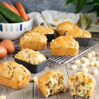 Muffin salati con zucchine e formaggio, uno spezzato a metà rivela l'interno soffice con verdure