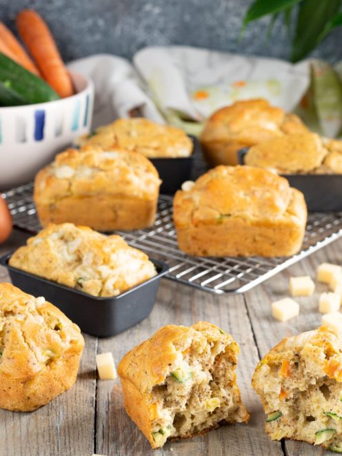 Muffin salati con zucchine e formaggio, uno spezzato a metà rivela l'interno soffice con verdure