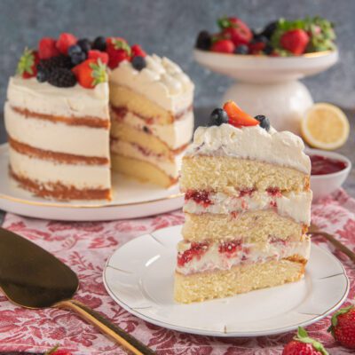 Naked cake senza glutine a strati con panna, frutti di bosco e fragole in cima