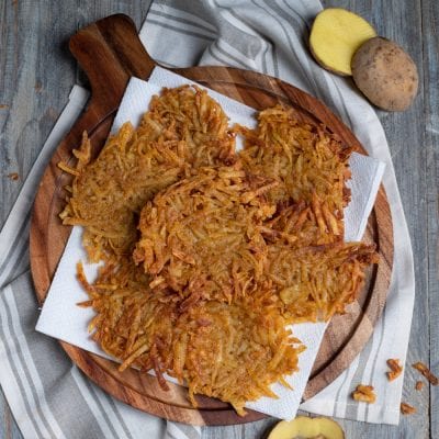 Patate hash brown croccanti e dorate, appoggiate su carta assorbente dopo la frittura