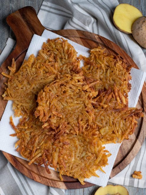 Patate hash brown croccanti e dorate, appoggiate su carta assorbente dopo la frittura