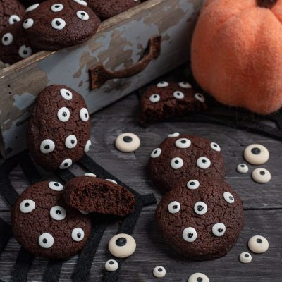 Biscotti di Halloween al cacao decorati con occhietti di zucchero, uno spezzato mostra l'interno morbido
