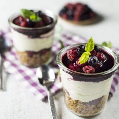 Cheesecake senza glutine in barattolo con base sbriciolata, crema e coulis di frutti di bosco guarnito di menta