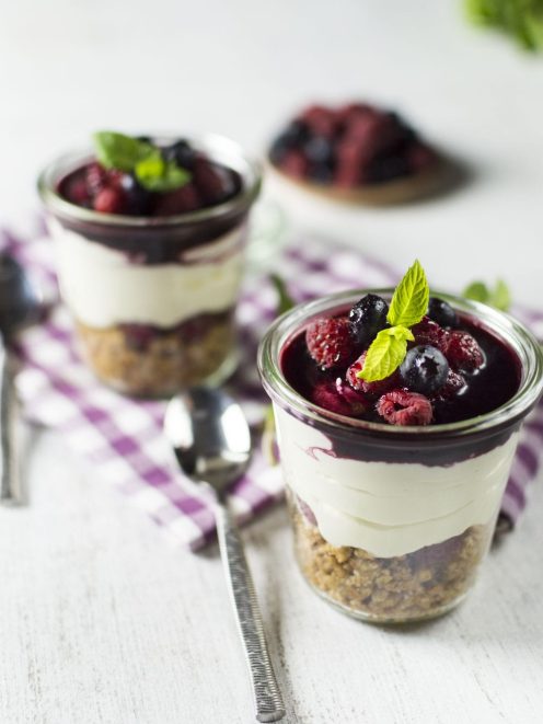 Cheesecake senza glutine in barattolo con base sbriciolata, crema e coulis di frutti di bosco guarnito di menta