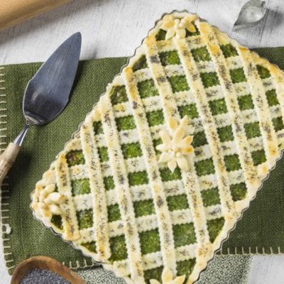 Crostata senza glutine con ricotta e spinaci, reticolo di pasta dorata con fiori decorativi e semi di papavero