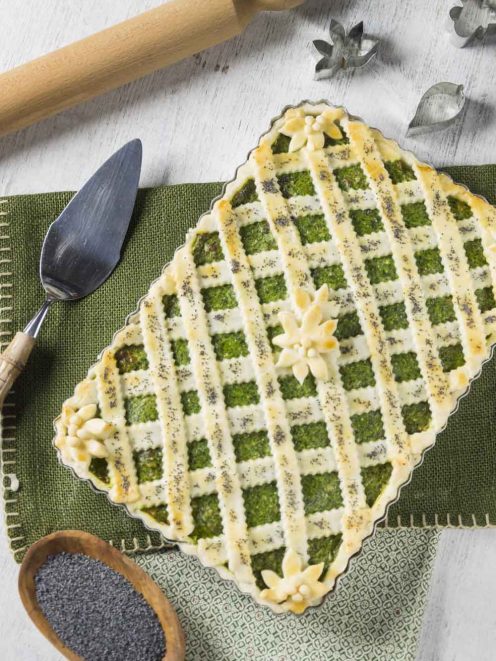Crostata senza glutine con ricotta e spinaci, reticolo di pasta dorata con fiori decorativi e semi di papavero