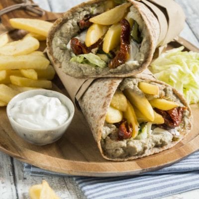 Piadina gyros di verdure farcita con hummus, pomodori secchi e patatine fritte, servita aperta a metà