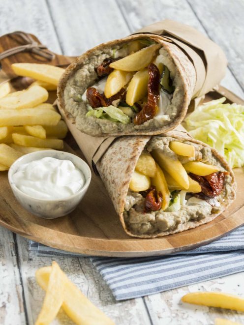 Piadina gyros di verdure farcita con hummus, pomodori secchi e patatine fritte, servita aperta a metà