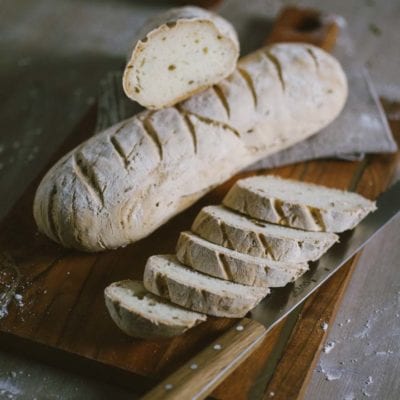 Pane senza glutine affettato su tagliere, con la mollica chiara e la crosta rustica ben visibile