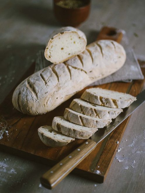 Pane senza glutine affettato su tagliere, con la mollica chiara e la crosta rustica ben visibile