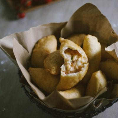 Panzerotti senza glutine fritti e dorati, uno aperto rivela il ripieno filante di mozzarella e pomodoro
