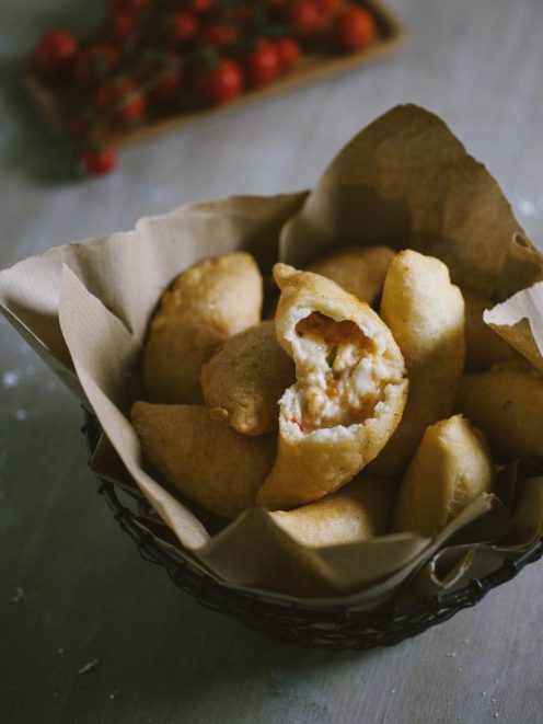 Panzerotti senza glutine fritti e dorati, uno aperto rivela il ripieno filante di mozzarella e pomodoro