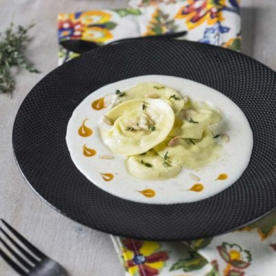 Ravioli cachi ricotta e pecorino in crema bianca con pinoli, timo fresco e gocce di salsa al caco