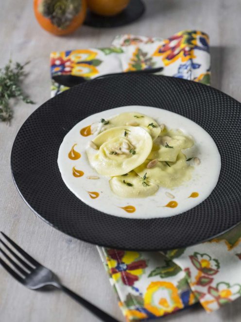 Ravioli cachi ricotta e pecorino in crema bianca con pinoli, timo fresco e gocce di salsa al caco