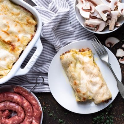 Cannelloni salsiccia e funghi gratinati serviti nel piatto con besciamella dorata