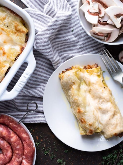 Cannelloni salsiccia e funghi gratinati serviti nel piatto con besciamella dorata
