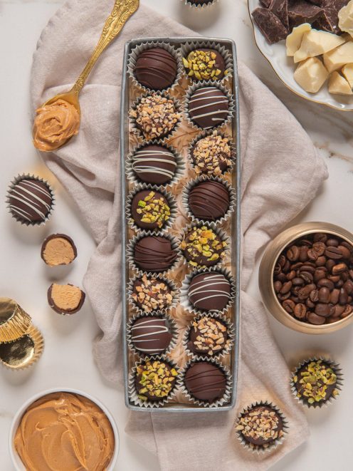 Praline al cioccolato fondente con granella di pistacchi, nocciole e glassa bianca in vassoio