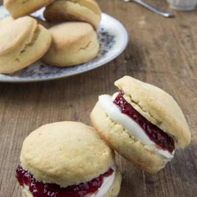Scones farciti con crema e confettura di frutti rossi, serviti su un piano di legno