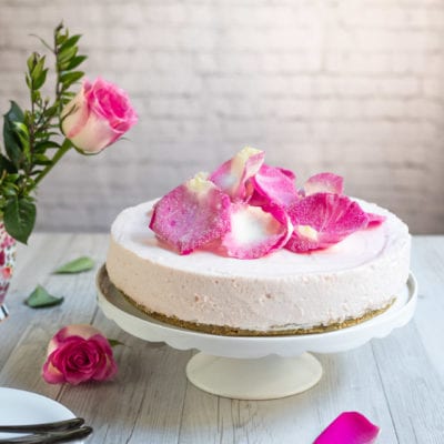 Cheesecake alle rose senza glutine con petali canditi sulla superficie e base di biscotti