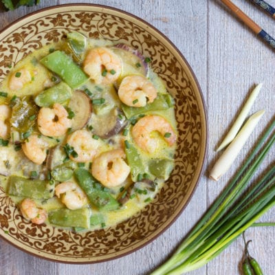 Curry verde con gamberi, taccole e melanzane in salsa cremosa, guarnito con erba cipollina