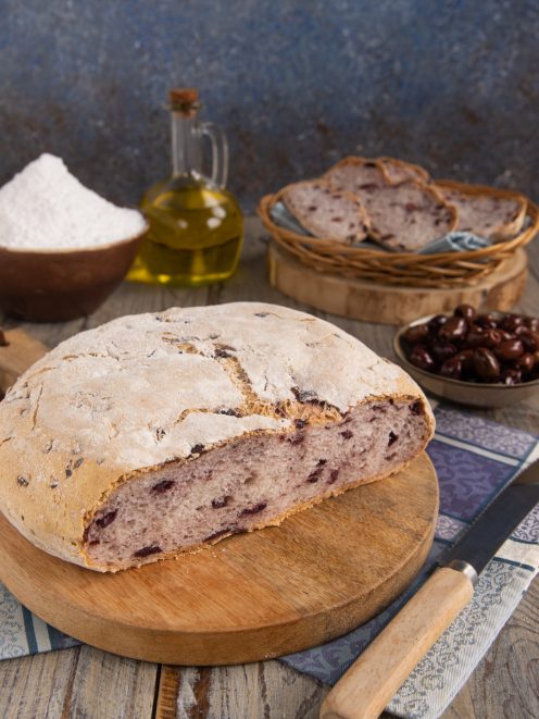 Pagnotta alle olive senza glutine tagliata a metà, con la mollica scura e le olive nere ben visibili