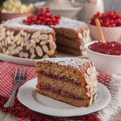 Torta di grano saraceno e ribes con strati di confettura, mandorle a lamelle sui bordi e zucchero a velo