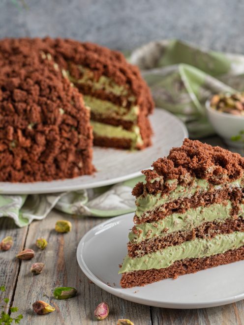 Torta mimosa al cioccolato a strati con crema al pistacchio, ricoperta di briciole di pan di Spagna al cacao
