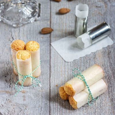 Cartucce napoletane avvolte in carta e legate con spago, con mandorle sullo sfondo