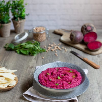 Hummus di barbabietola cremoso con foglioline di menta e un filo d'olio, servito con pane pita