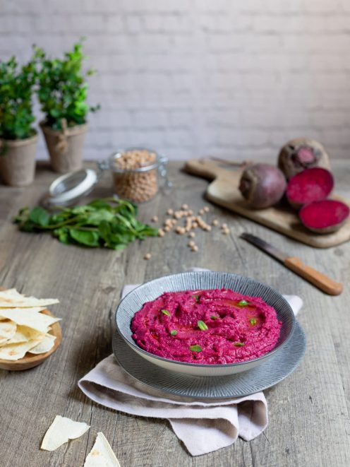 Hummus di barbabietola cremoso con foglioline di menta e un filo d'olio, servito con pane pita