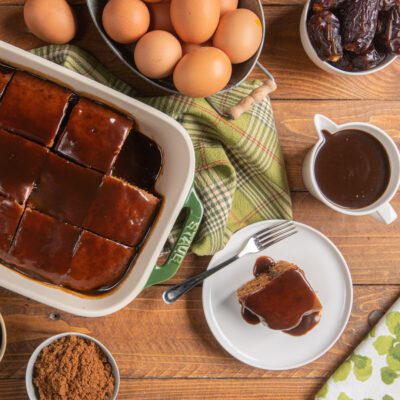Sticky toffee pudding tagliato a quadrotti e glassato con salsa al caramello, una porzione servita a parte