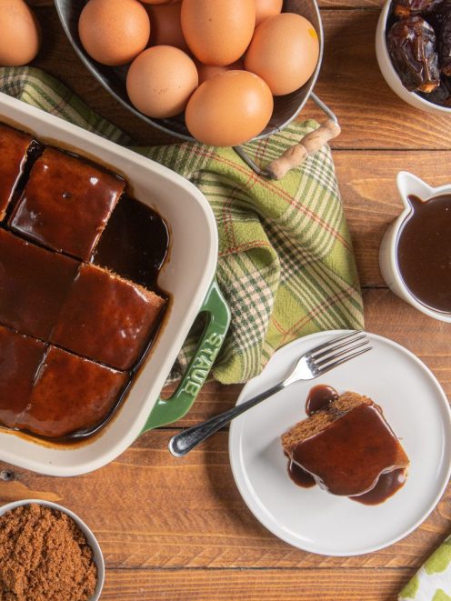 Sticky toffee pudding tagliato a quadrotti e glassato con salsa al caramello, una porzione servita a parte