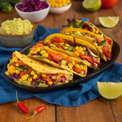 Tacos con guacamole, mais, pomodoro e cavolo rosso serviti in fila su vassoio