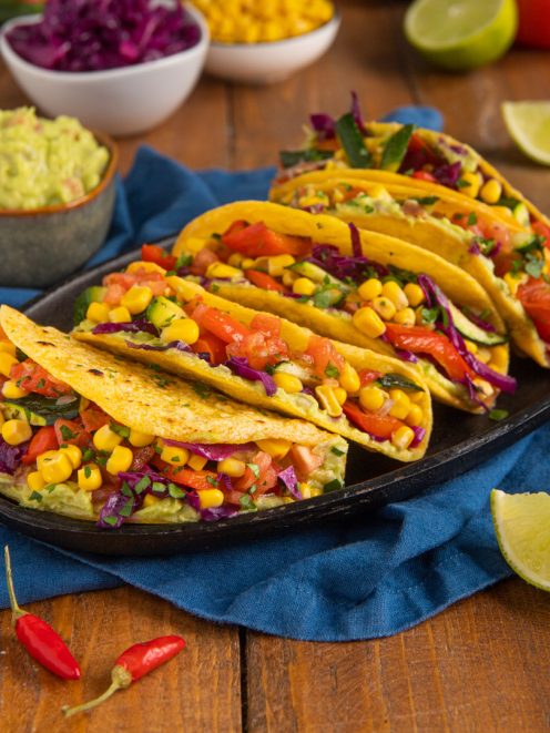 Tacos con guacamole, mais, pomodoro e cavolo rosso serviti in fila su vassoio